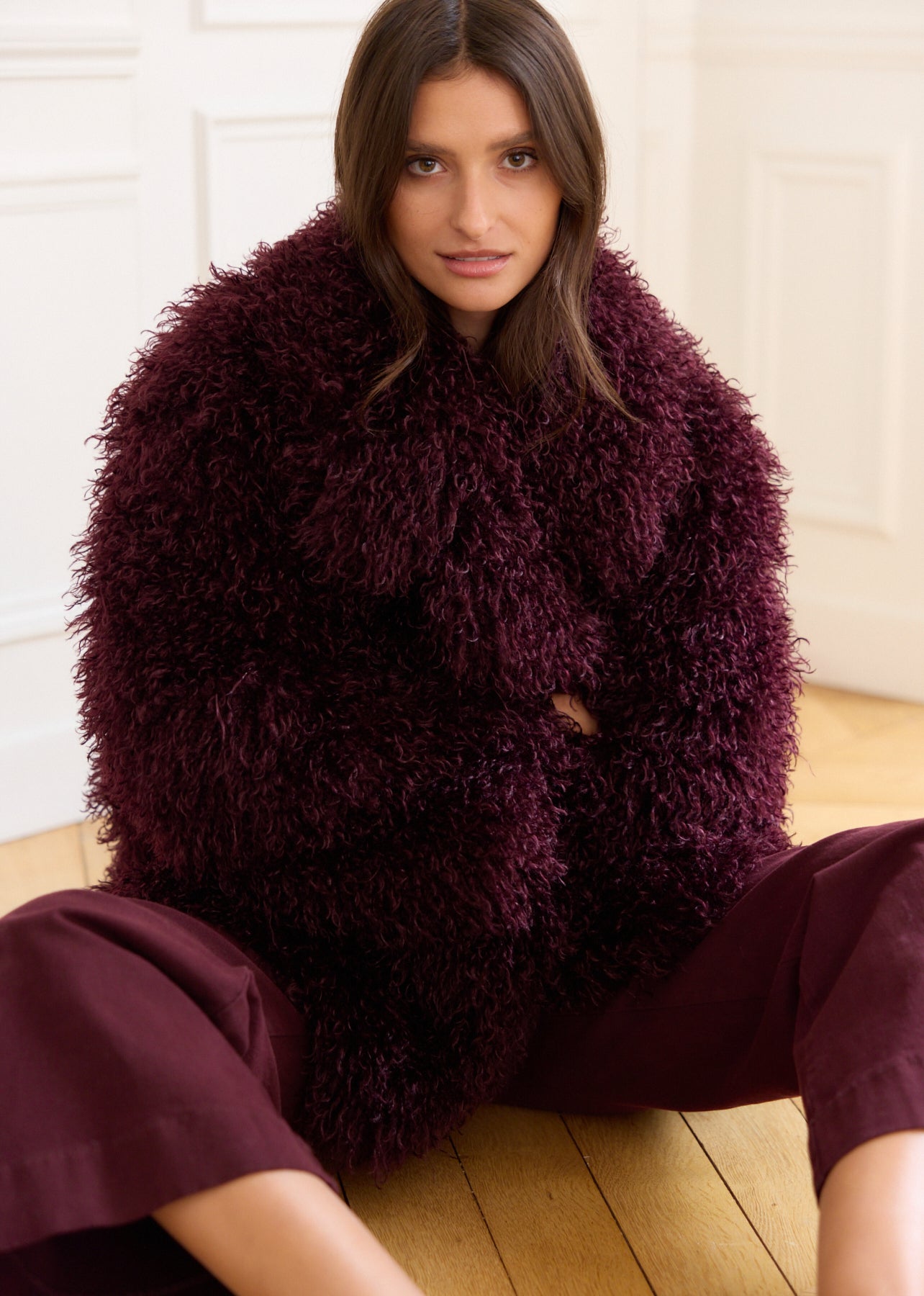 Burgundy faux fur coat with curly hair, long sleeves, and a round